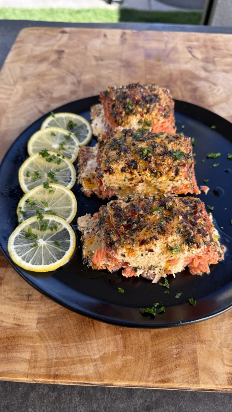 Smoked crab-stuffed salmon fillet on a plate garnished with parsley and lemon wedges.