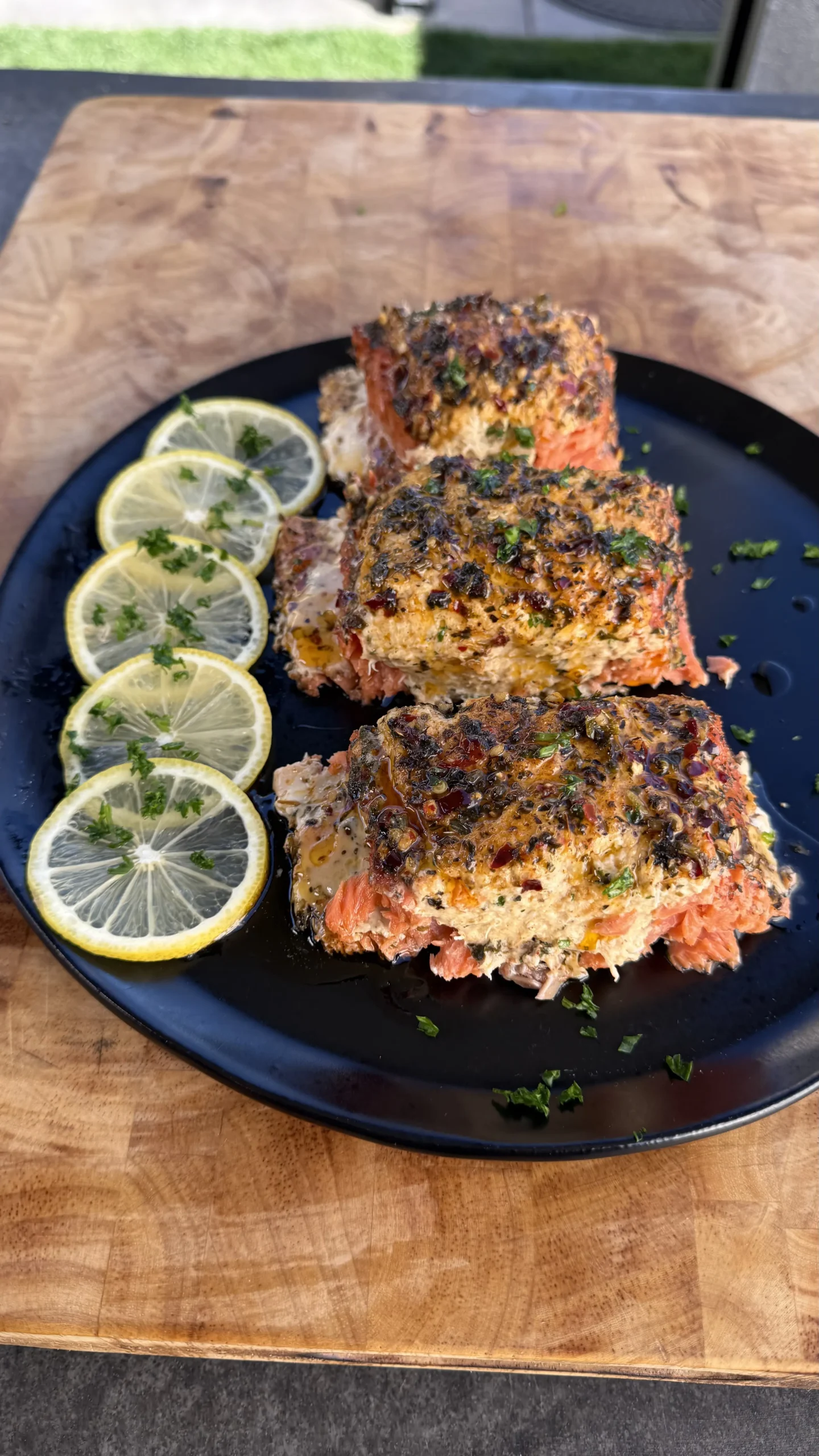 Smoked crab-stuffed salmon fillet on a plate garnished with parsley and lemon wedges.