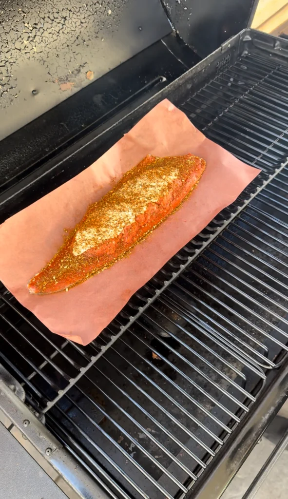 Stuffed salmon fillet on a smoker grate, cooking at 250°F for perfect texture.