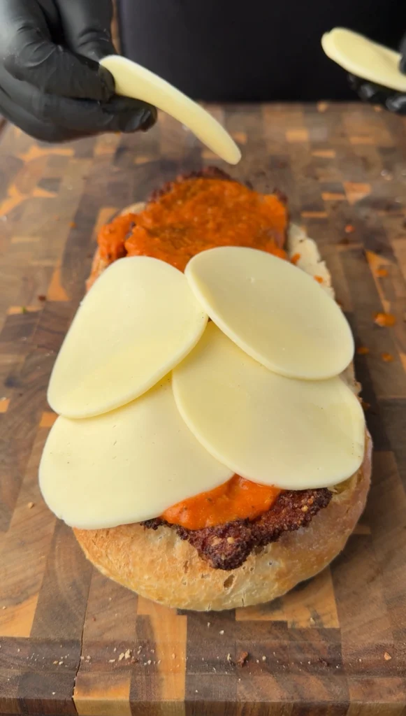 adding cheese and finishing the chicken parmesan bread boat