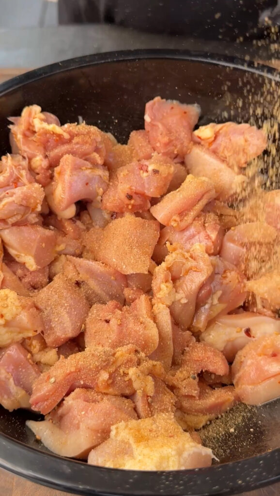 chopped chicken thighs in a bowl with seasoning