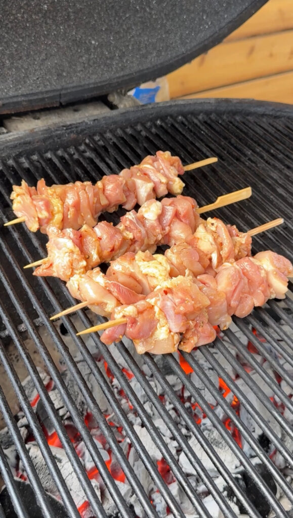 cooking chicken skewers on a charcoal grill
