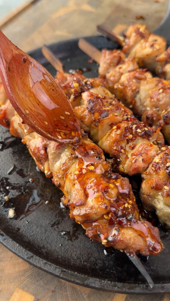 chili oil on the chicken skewers on the plate