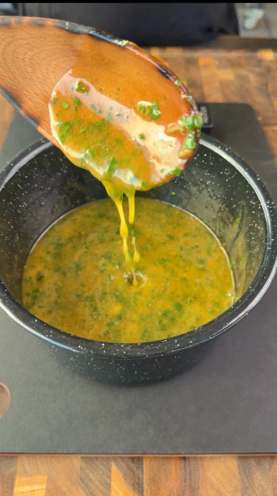 Melted butter with garlic, thyme, rosemary, parsley, dill, and honey simmering in a small saucepan.