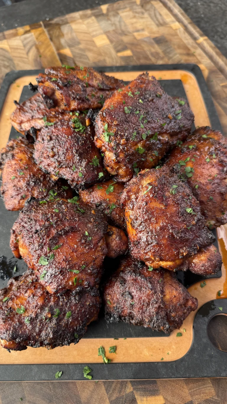 Finished honey chipotle grilled chicken thighs on slate serving board with fresh parsley garnish, showing caramelized glaze and perfect color