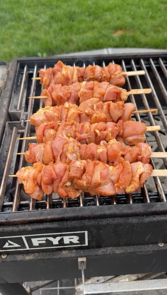 chicken skewers over top of a hot flame