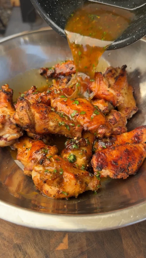 pouring the sauce over top of the wings