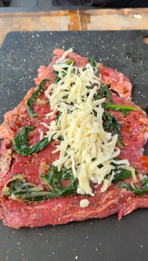 Butterflied skirt steak topped with sautéed spinach mixture and shredded mozzarella cheese before rolling into pinwheels