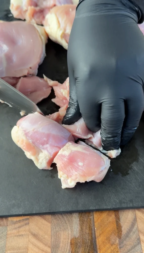 cubing chicken thighs on a cutting board