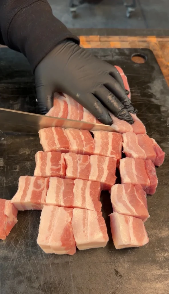chopped up pork belly on a cutting board