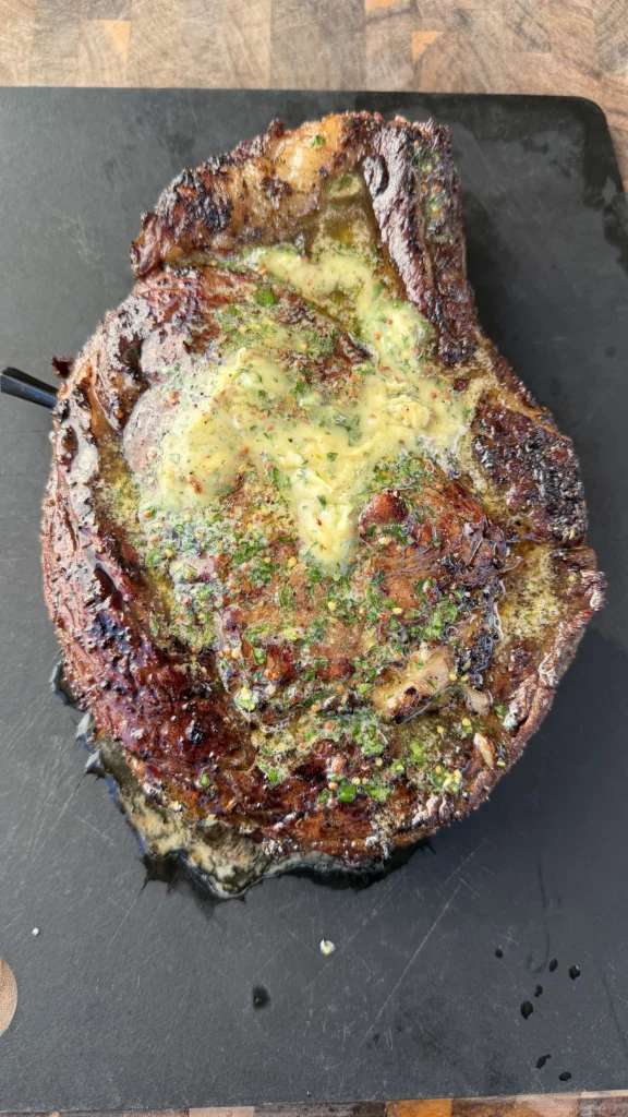 cowboy steak on a.cutting board with honey butetr