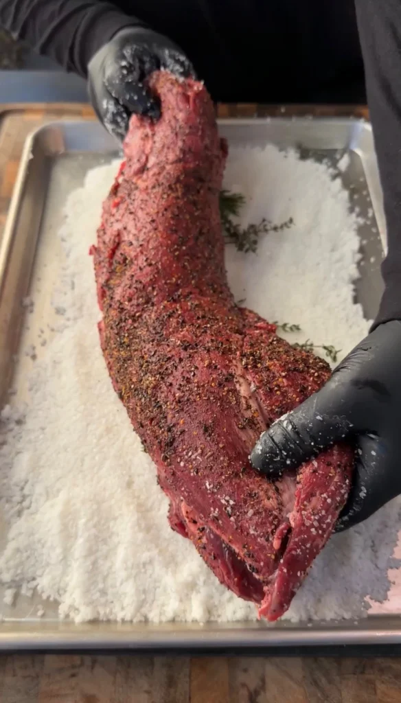 beef tenderloin being placed in salt