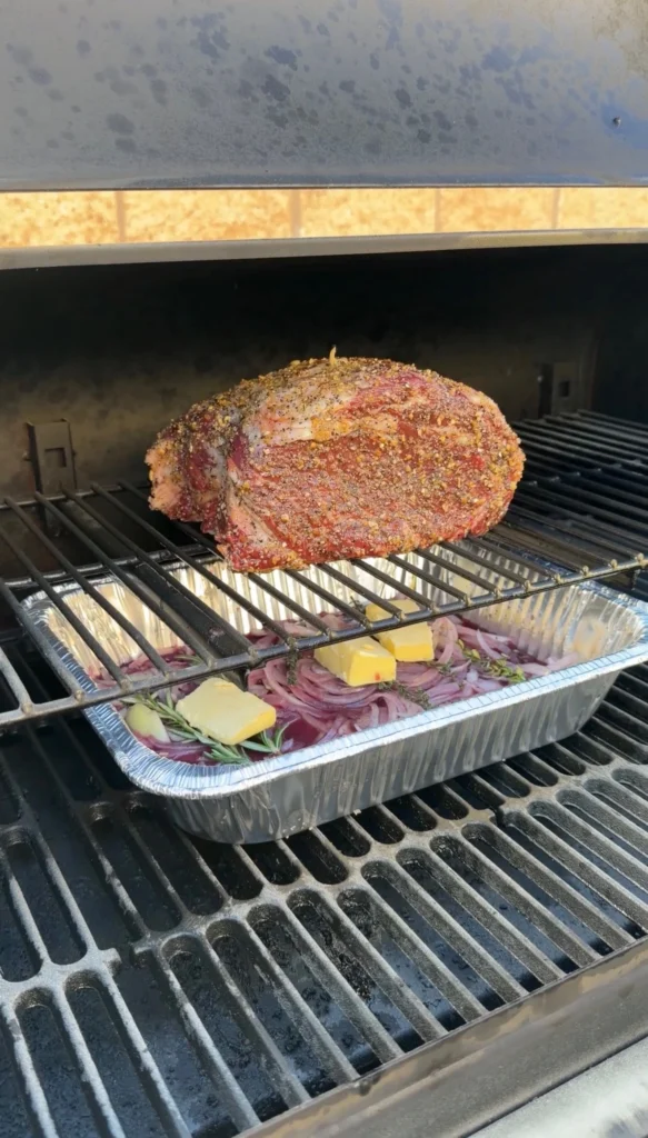prime rib in the smoker with a drip pan