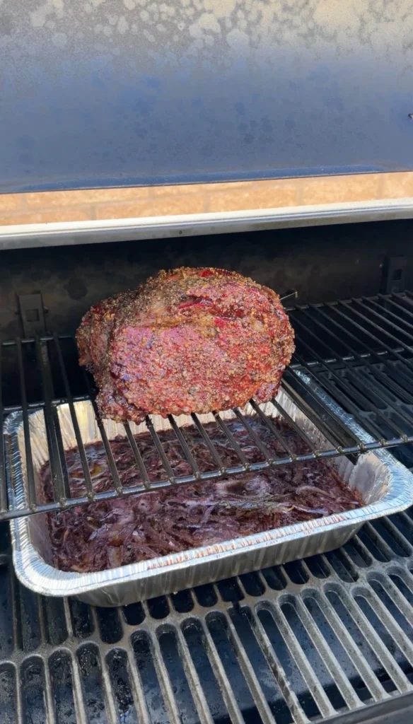 prime rib in the smoker with a drip pan