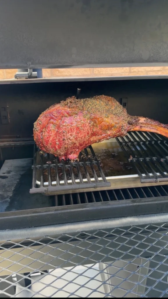 rib roast on the smoker with a drip pan underneath 