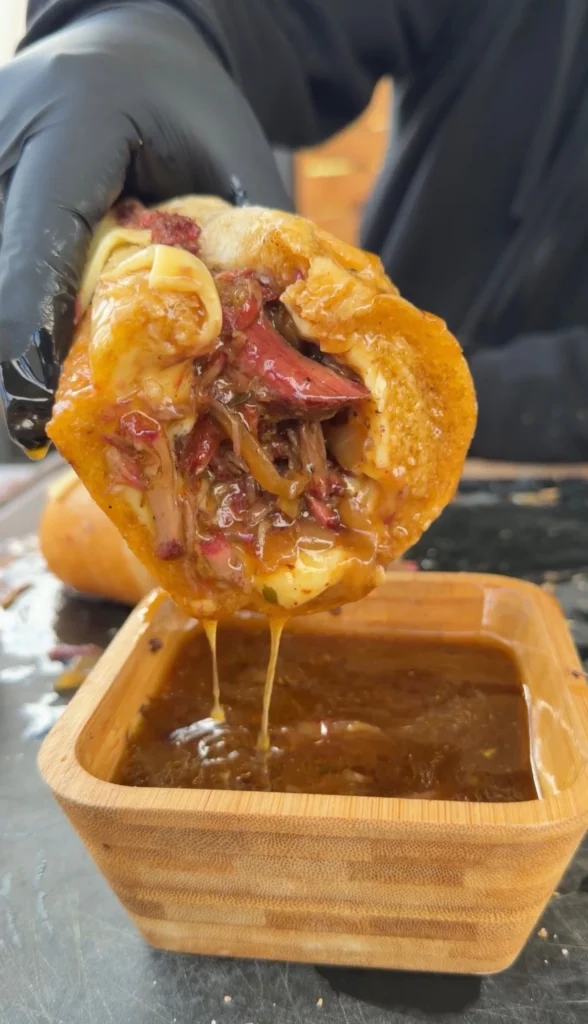 pulled beef sandwich being dipped in au jus