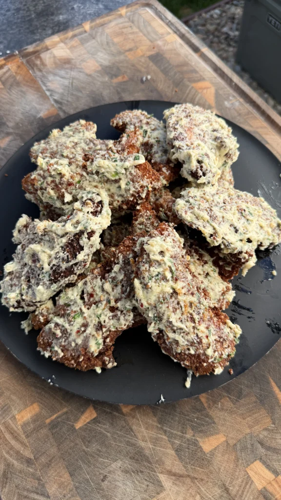 Plate of crispy fried garlic Parmesan chicken tenders coated in creamy sauce on a black plate