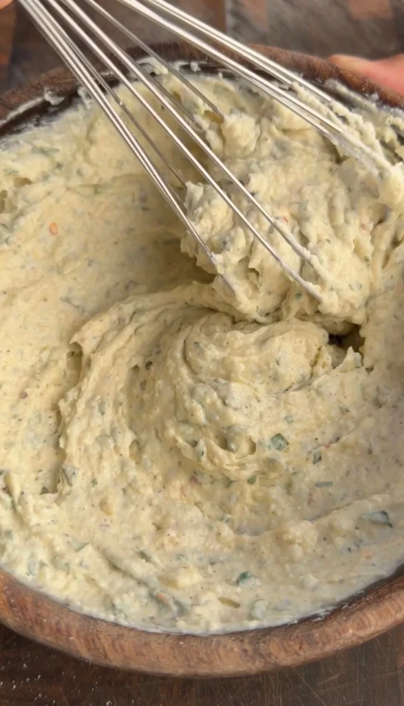 Garlic Parmesan mayo sauce being whisked smooth in a wooden bowl
