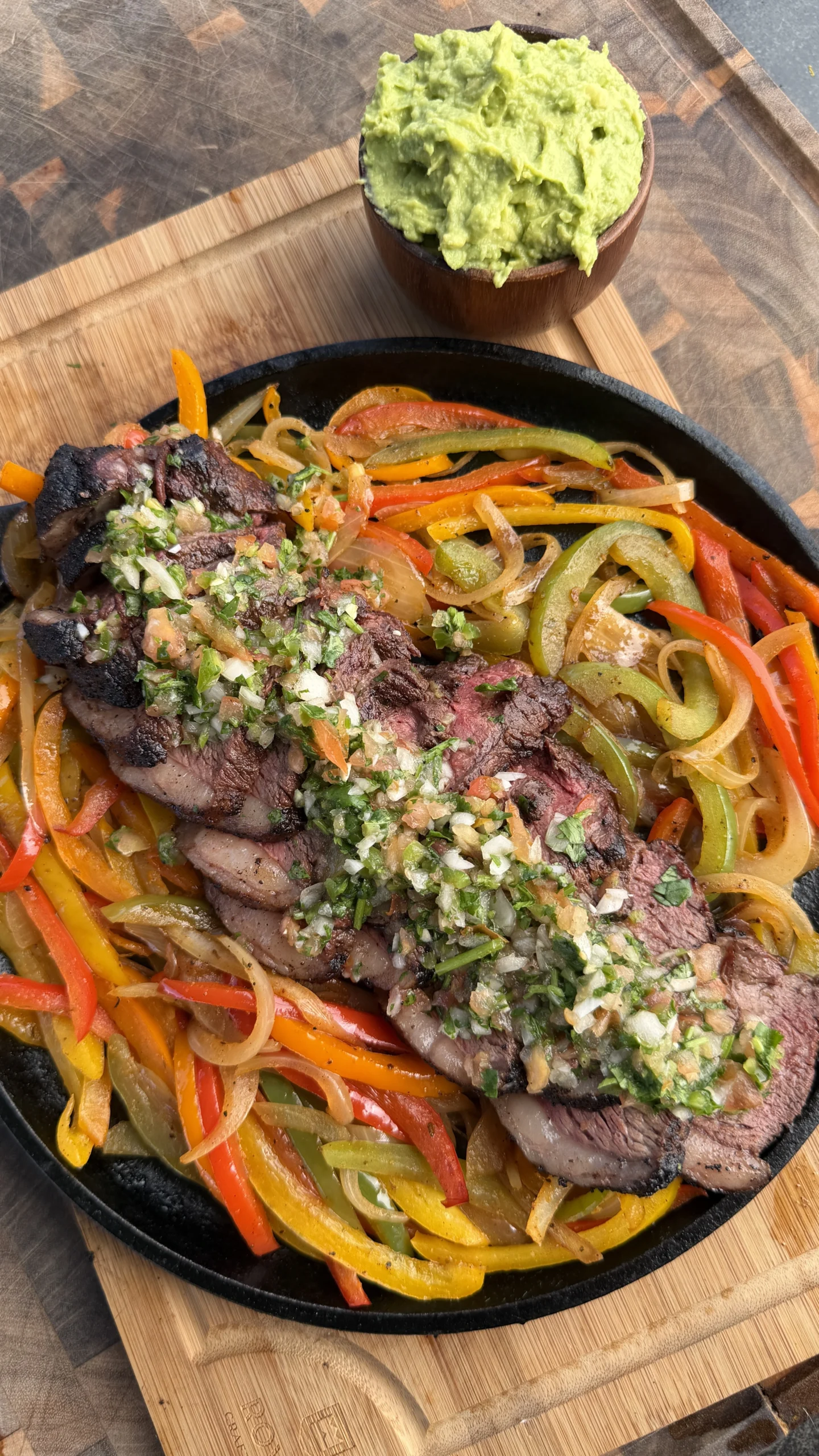 Assembled picanha fajita on a flour tortilla with sliced steak, charred peppers, guacamole, and pico de gallo