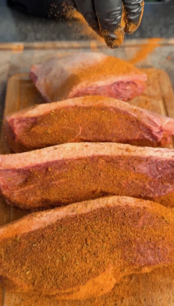 Four picanha steaks generously coated with carne asada seasoning on a cutting board