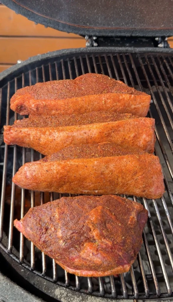 Four seasoned picanha steaks placed on a kamado grill grates for the initial sear