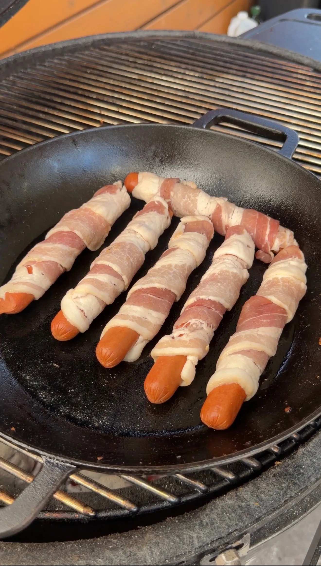 Bacon-wrapped chile relleno hot dogs cooking in pan