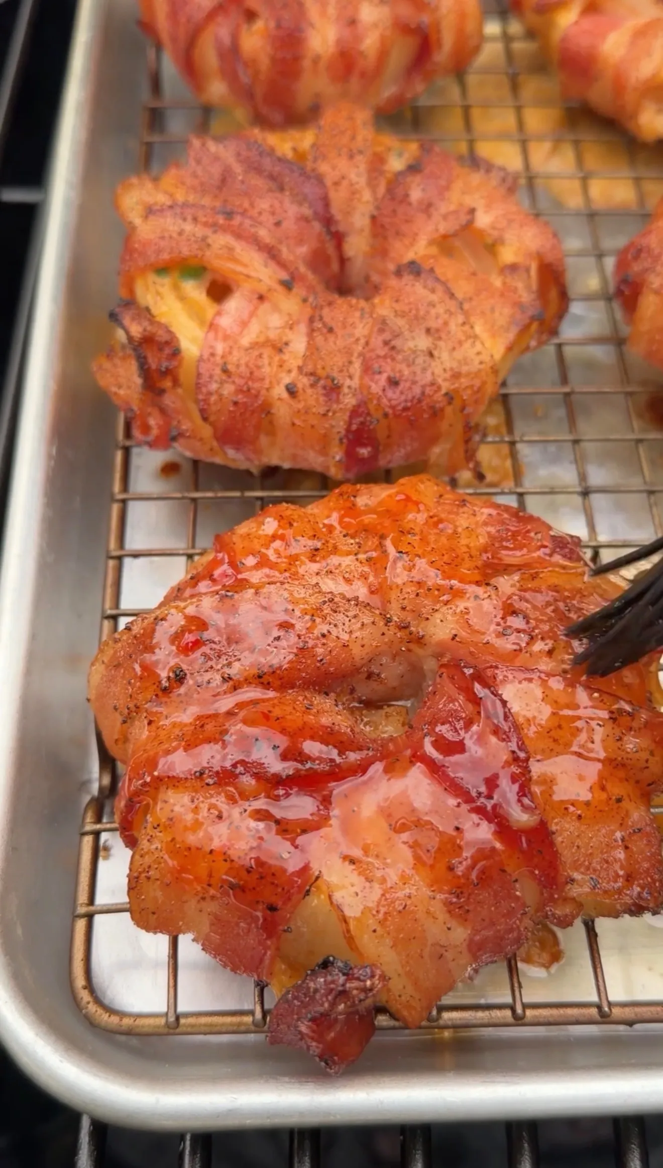 Golden bacon-wrapped crab stuffed onion rings cooling on wire rack, glistening with rendered fat and seasoning