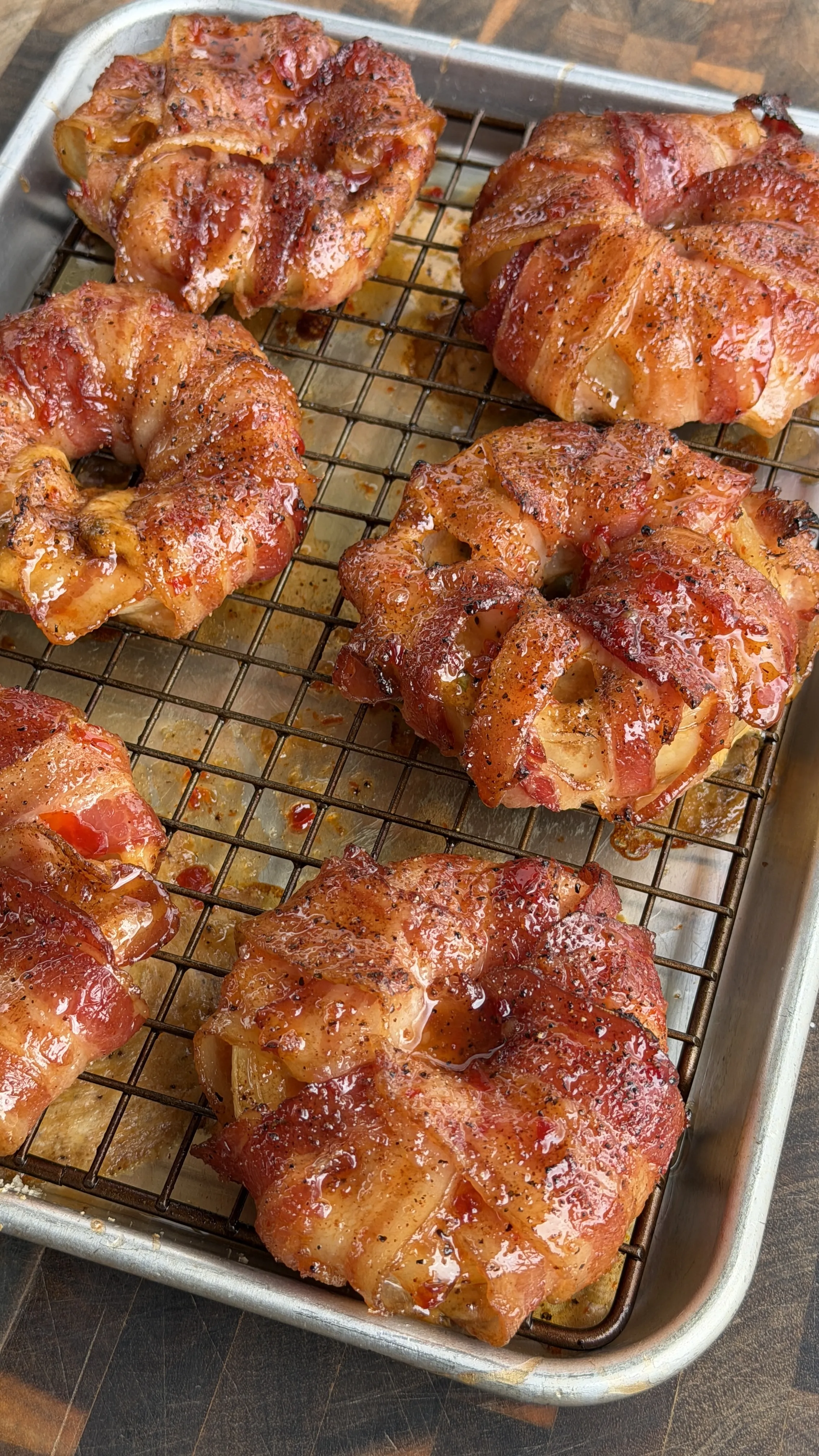 Golden brown bacon-wrapped crab stuffed onion rings cooling on wire rack over baking sheet