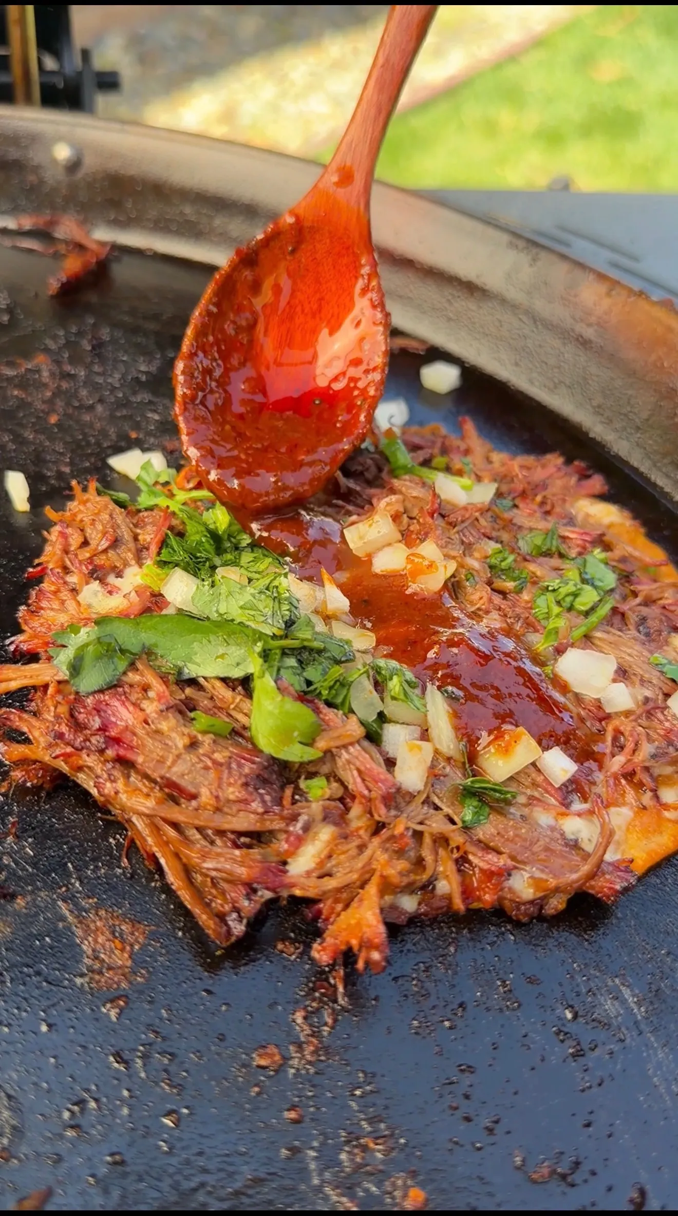 Birria meat cooking with red sauce and ladle