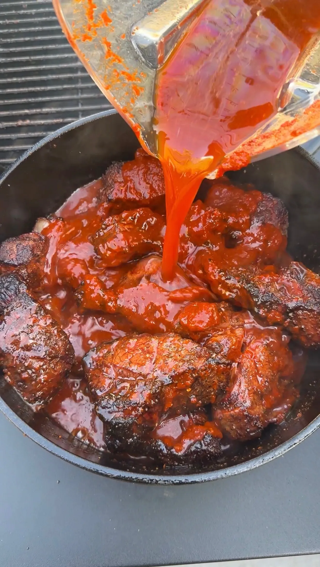 Birria meat with red consommé sauce in cast iron