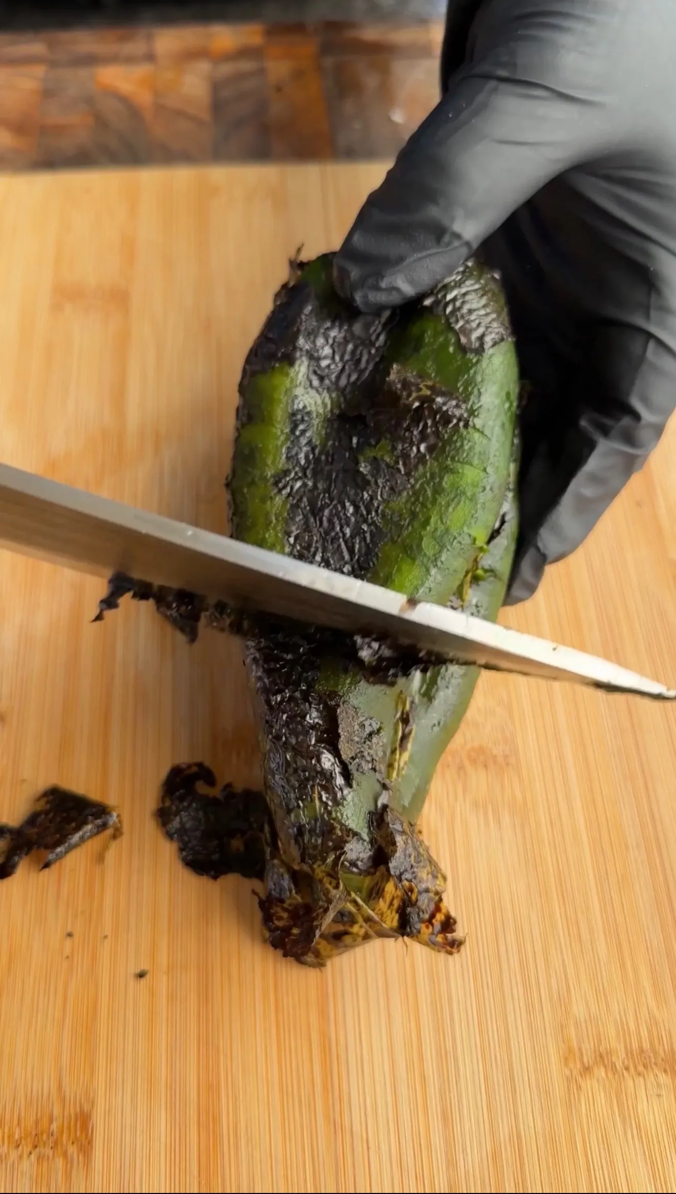 Charred poblano pepper being peeled with knife
