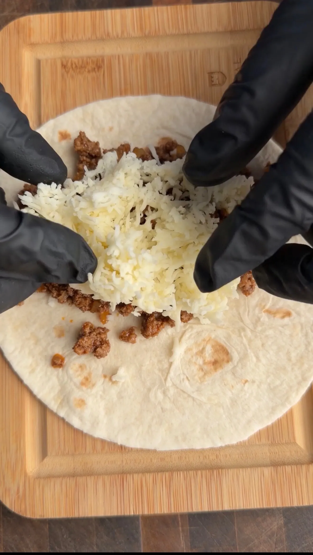Cheesy beef taquitos being assembled on tortillas