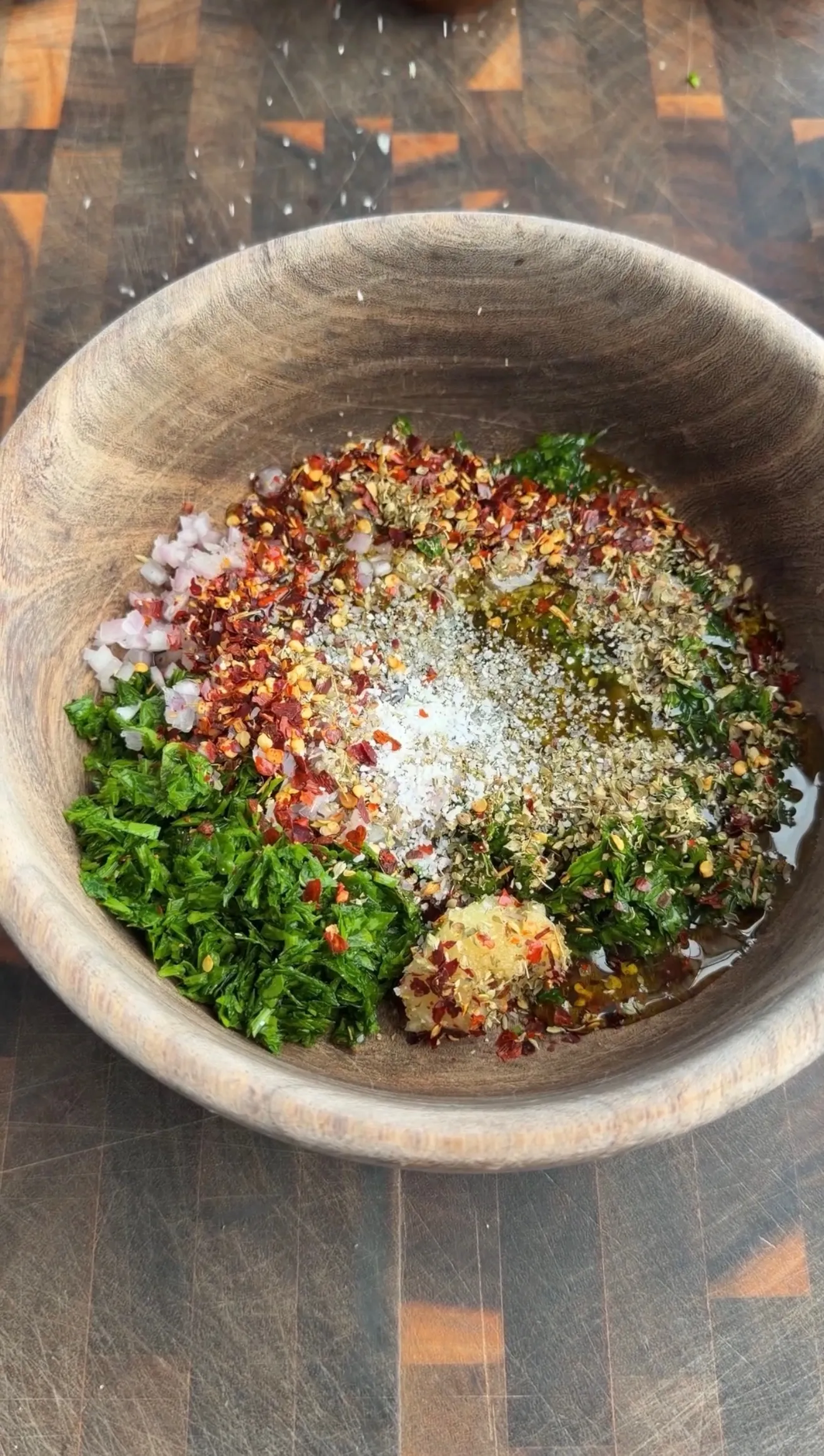 Chimichurri ingredients in wooden bowl during preparation