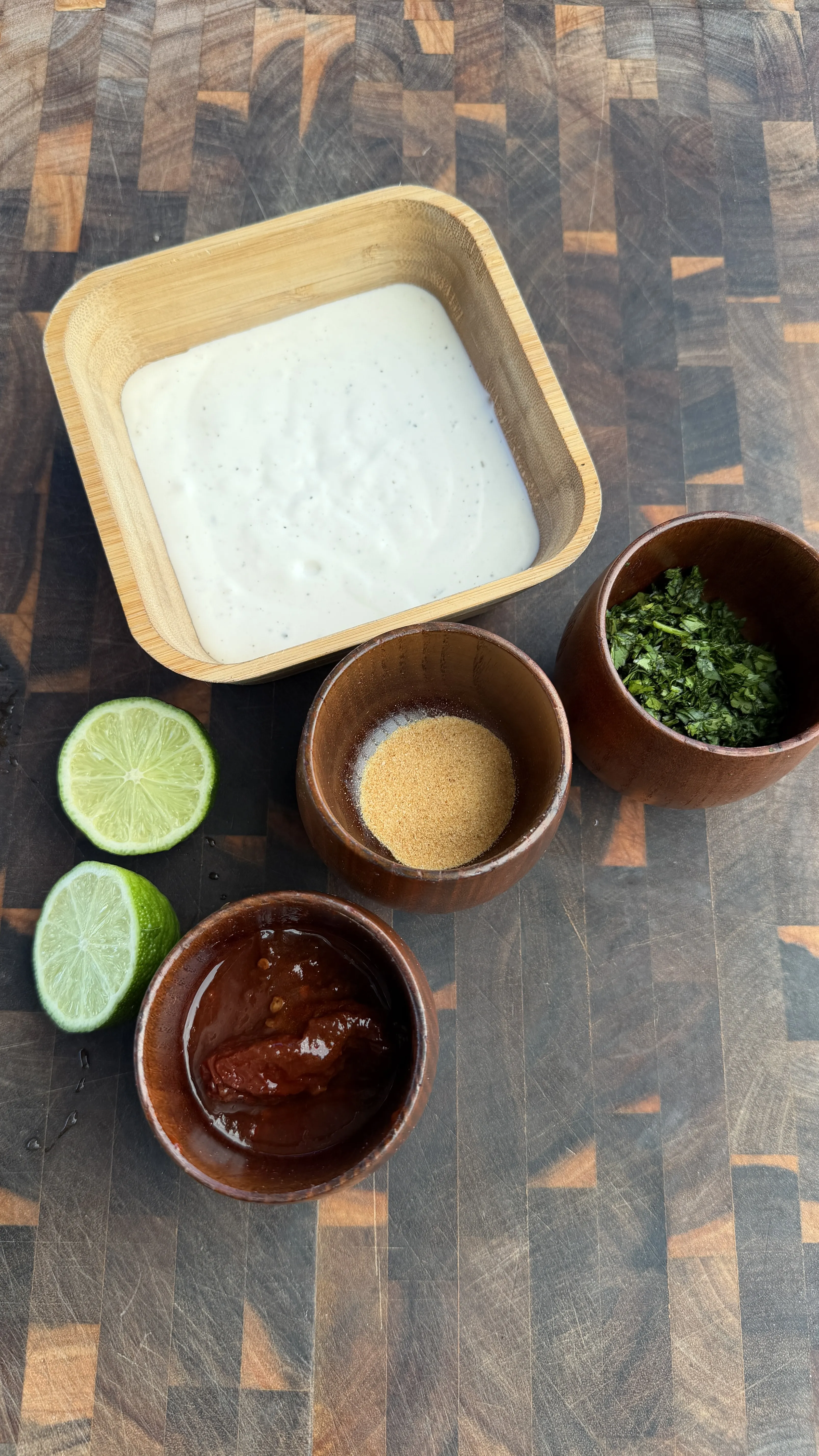 Chipotle ranch ingredients in wooden bowls with lime