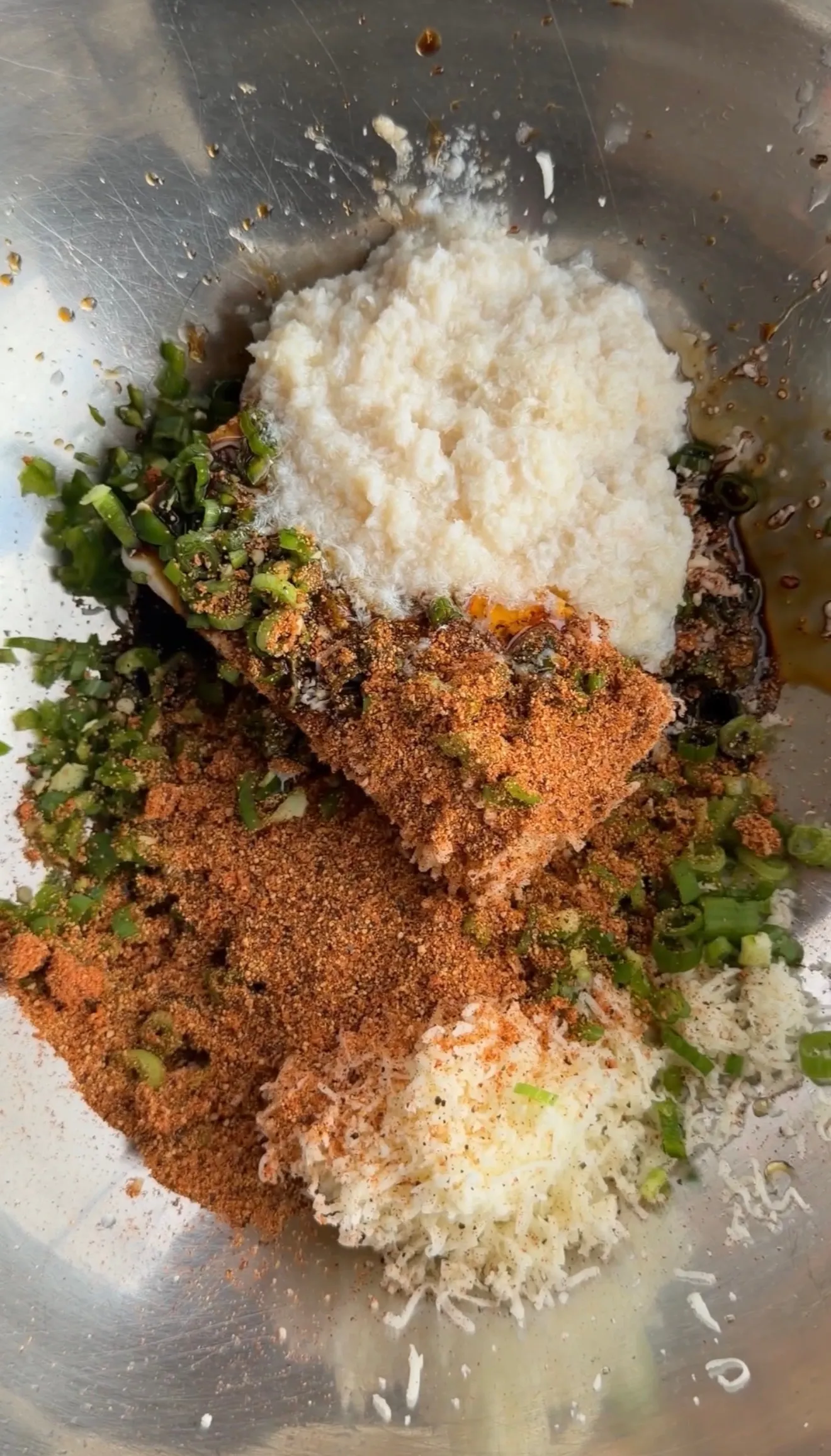 Raw crab stuffing ingredients mixed in stainless steel bowl with breadcrumbs, herbs, and seasonings