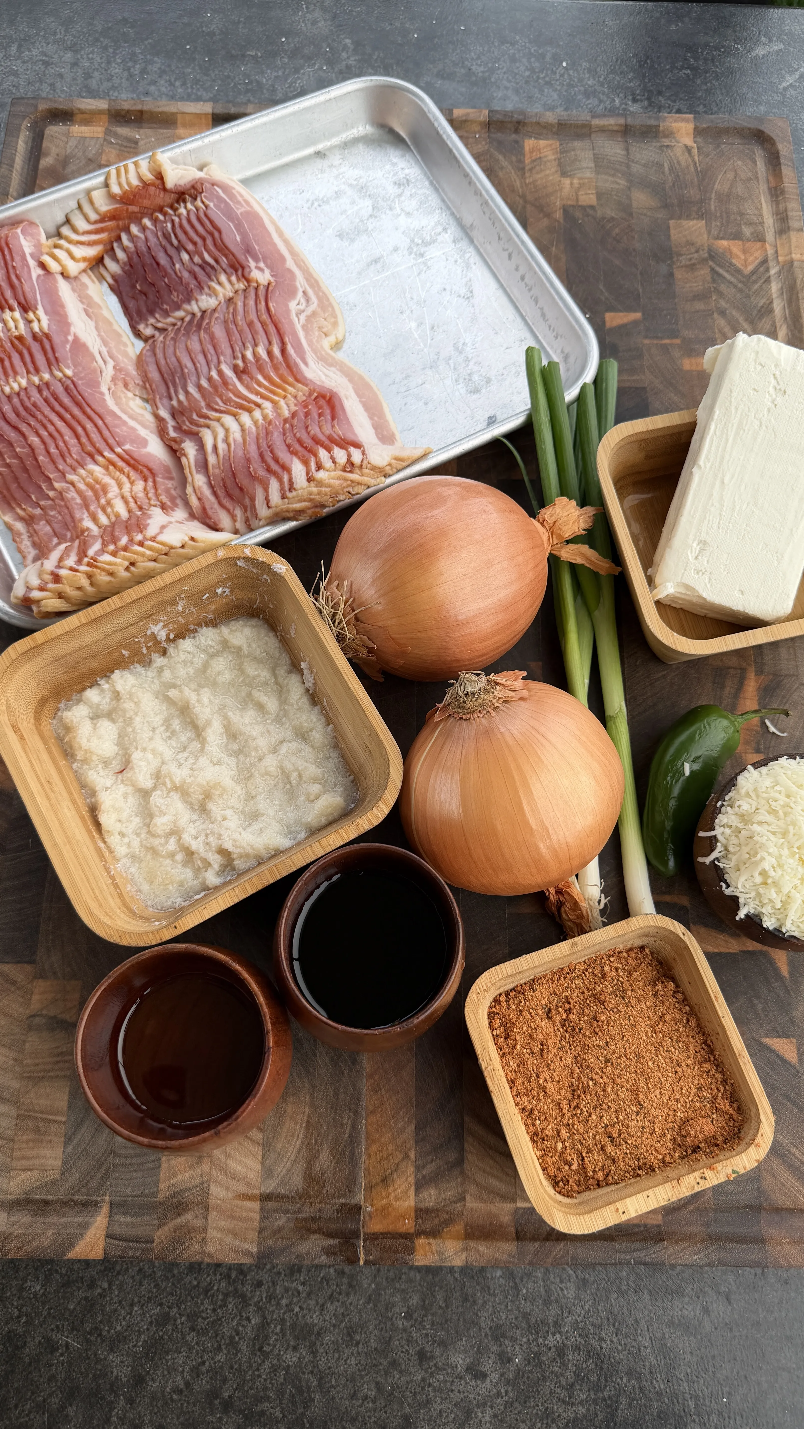 Raw ingredients for crab stuffed bacon-wrapped onion rings including sliced bacon, onions, crab meat, and seasonings