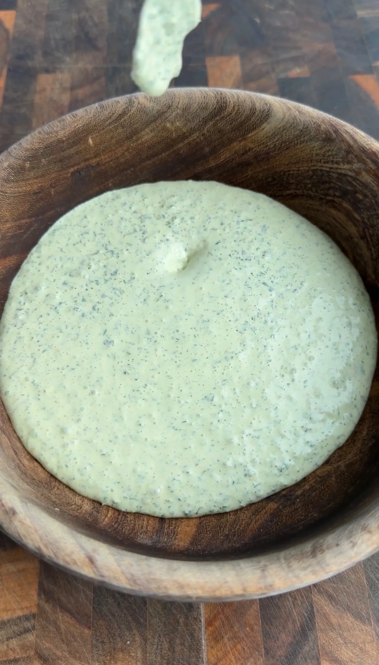 Creamy green cilantro lime sauce in wooden bowl