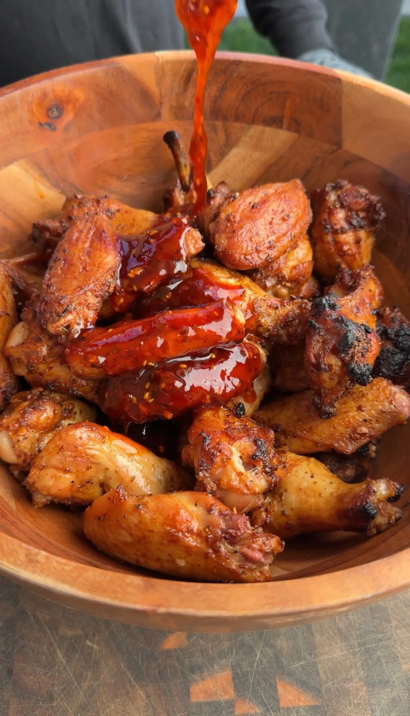 Fast smoked wings drizzled with sauce in wooden bowl