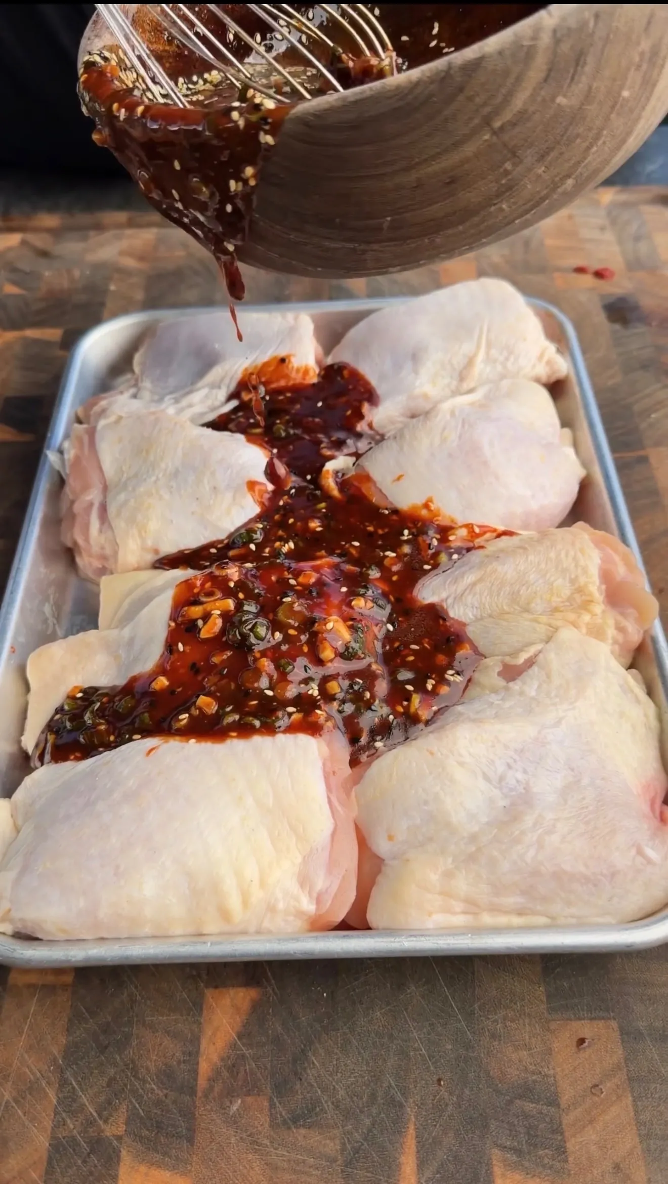 Garlic chili sesame marinade on chicken thighs in baking pan