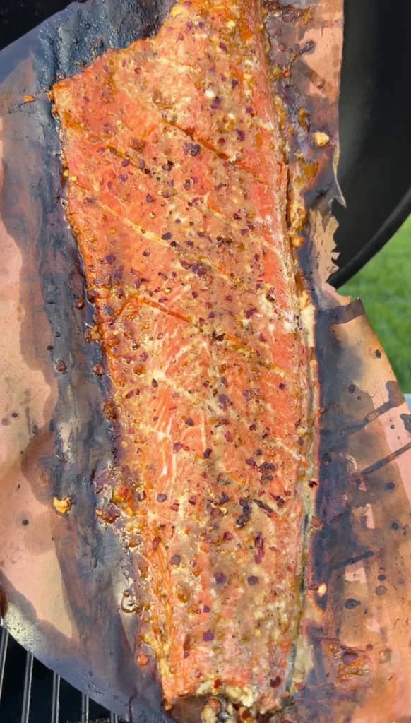 Garlic soy honey smoked salmon fillet with seasoning on cedar plank after grilling