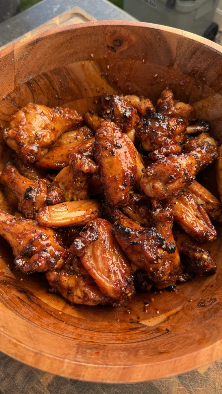 Glossy glazed smoked chicken wings with caramelized coating served in a rustic wooden bowl