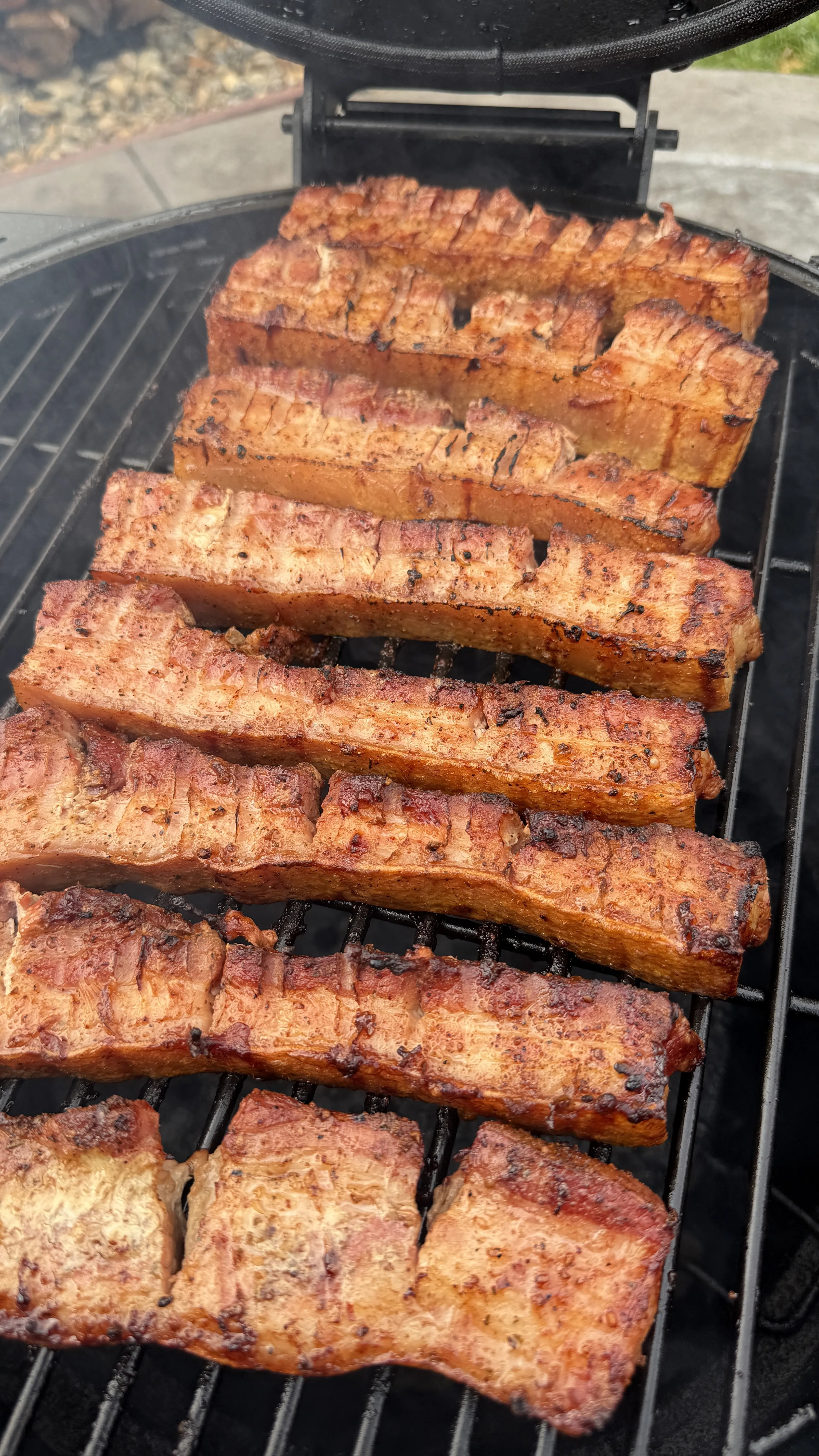 Grilled pork belly strips on grill grates