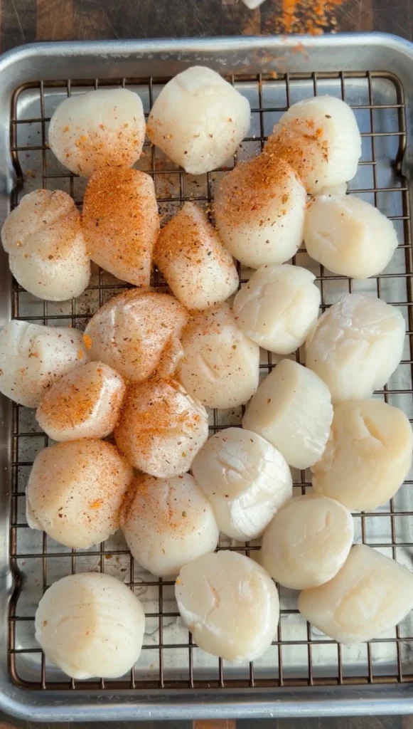 Seared scallops with paprika seasoning cooling on wire rack, some golden brown and others pale white