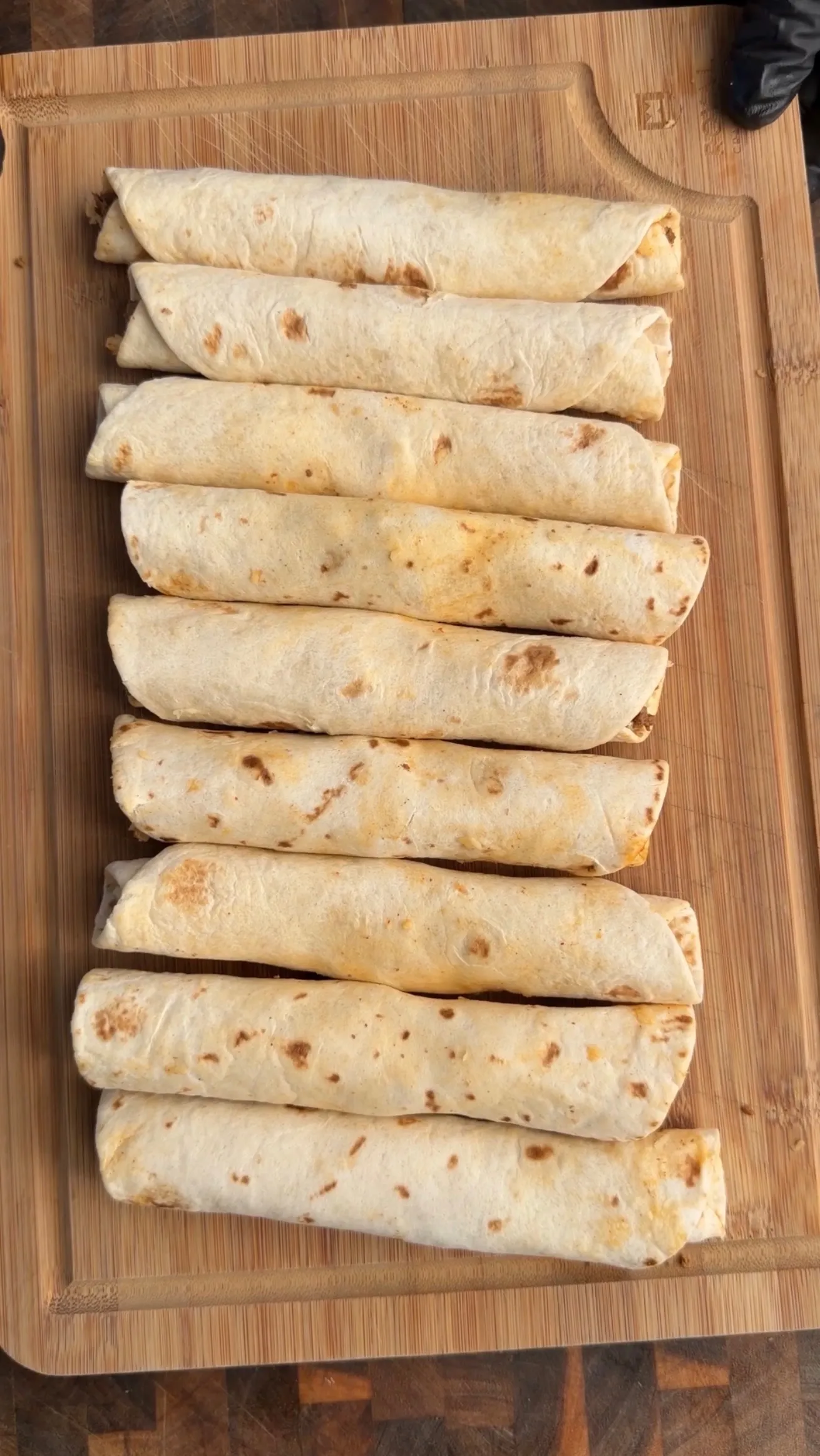 Homemade cheesy beef taquitos rolled on cutting board
