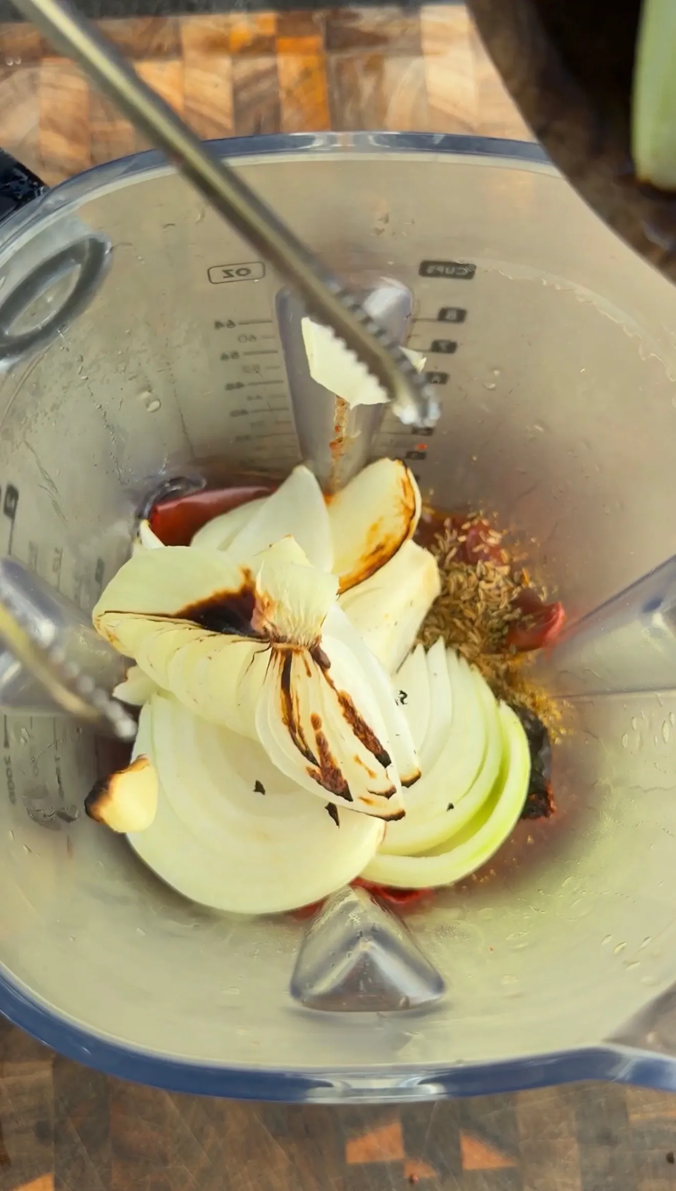 Onions and chiles blending into birria consommé in food processor