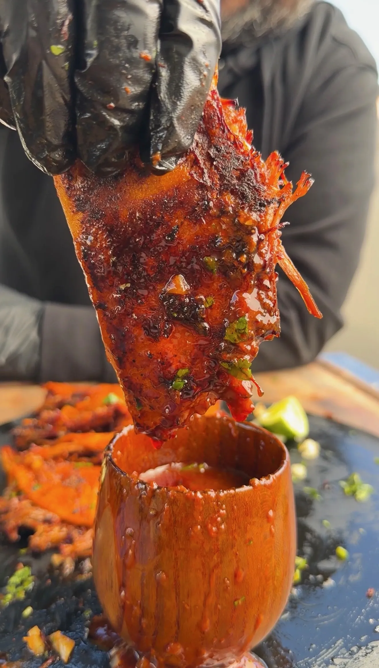 Quesa birria consommé being poured into wooden cup