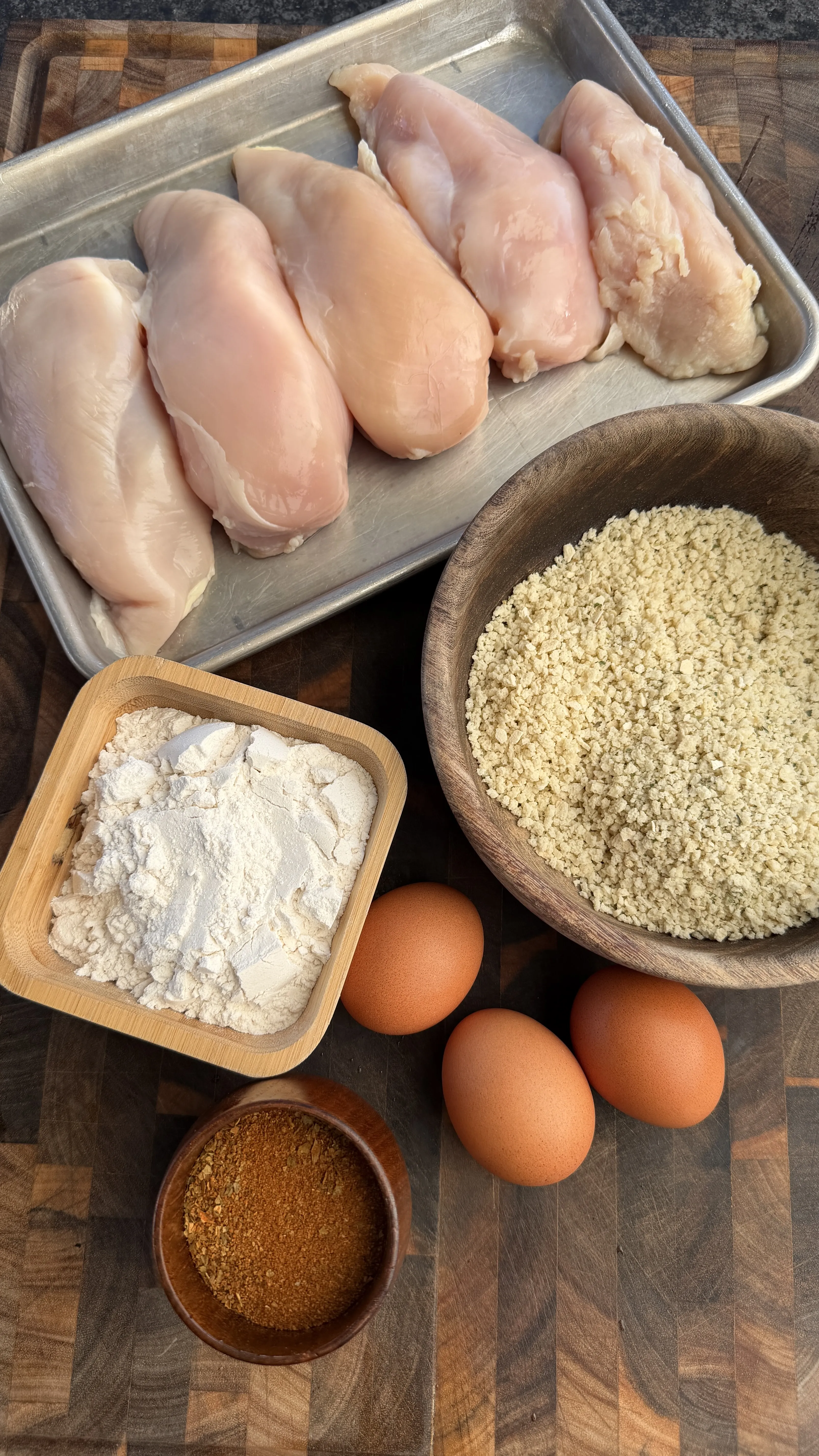 Raw chicken breasts and breading ingredients prep