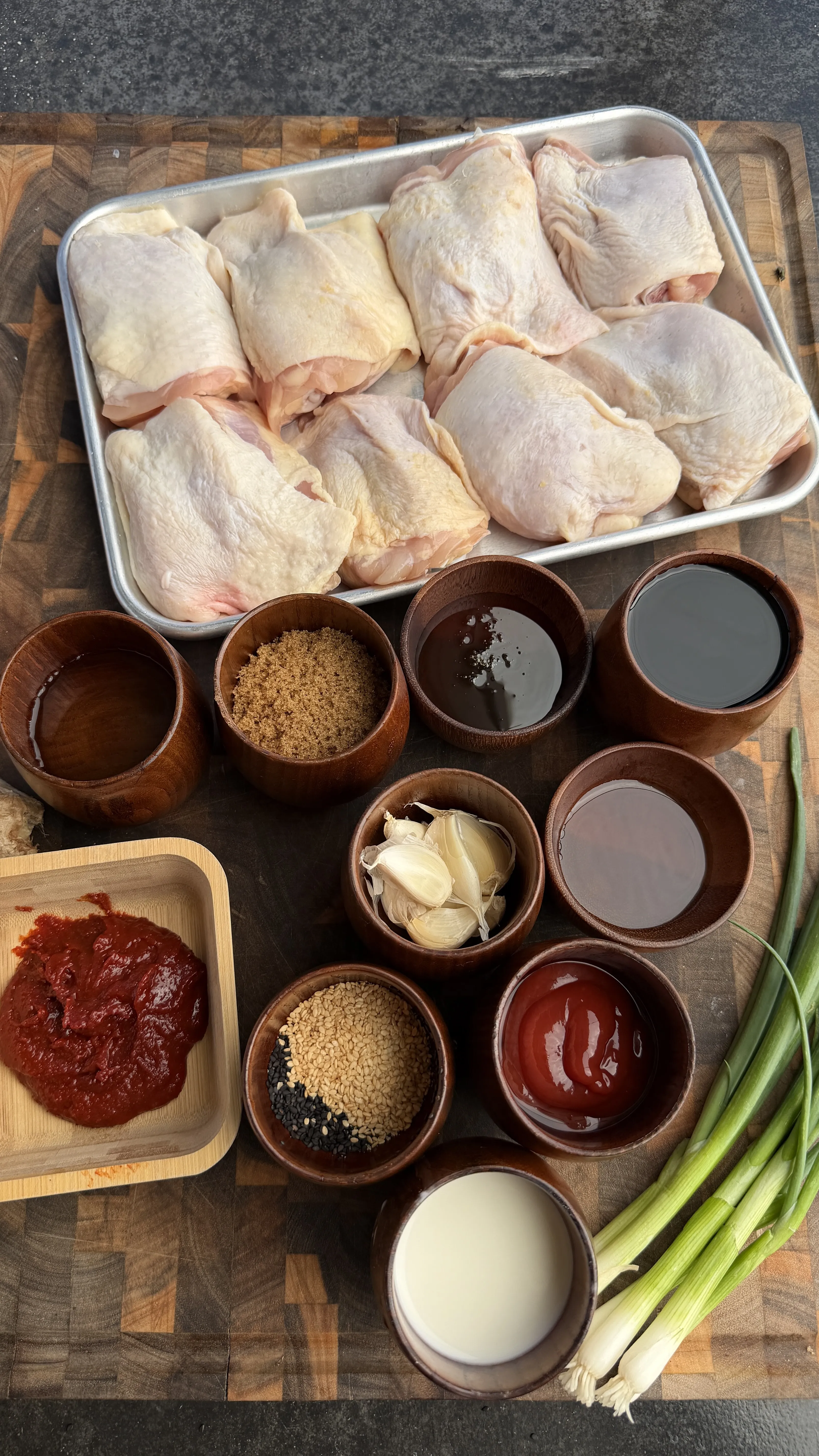 Raw chicken thighs with Asian marinade ingredients during prep