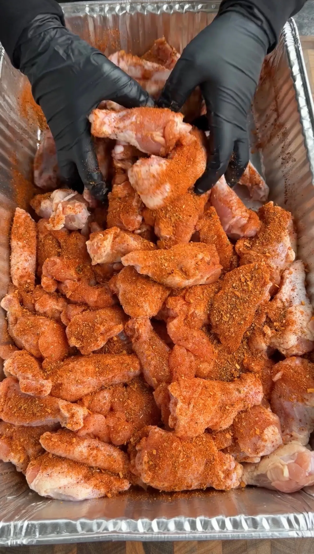 Raw chicken wings coated with paprika seasoning on foil