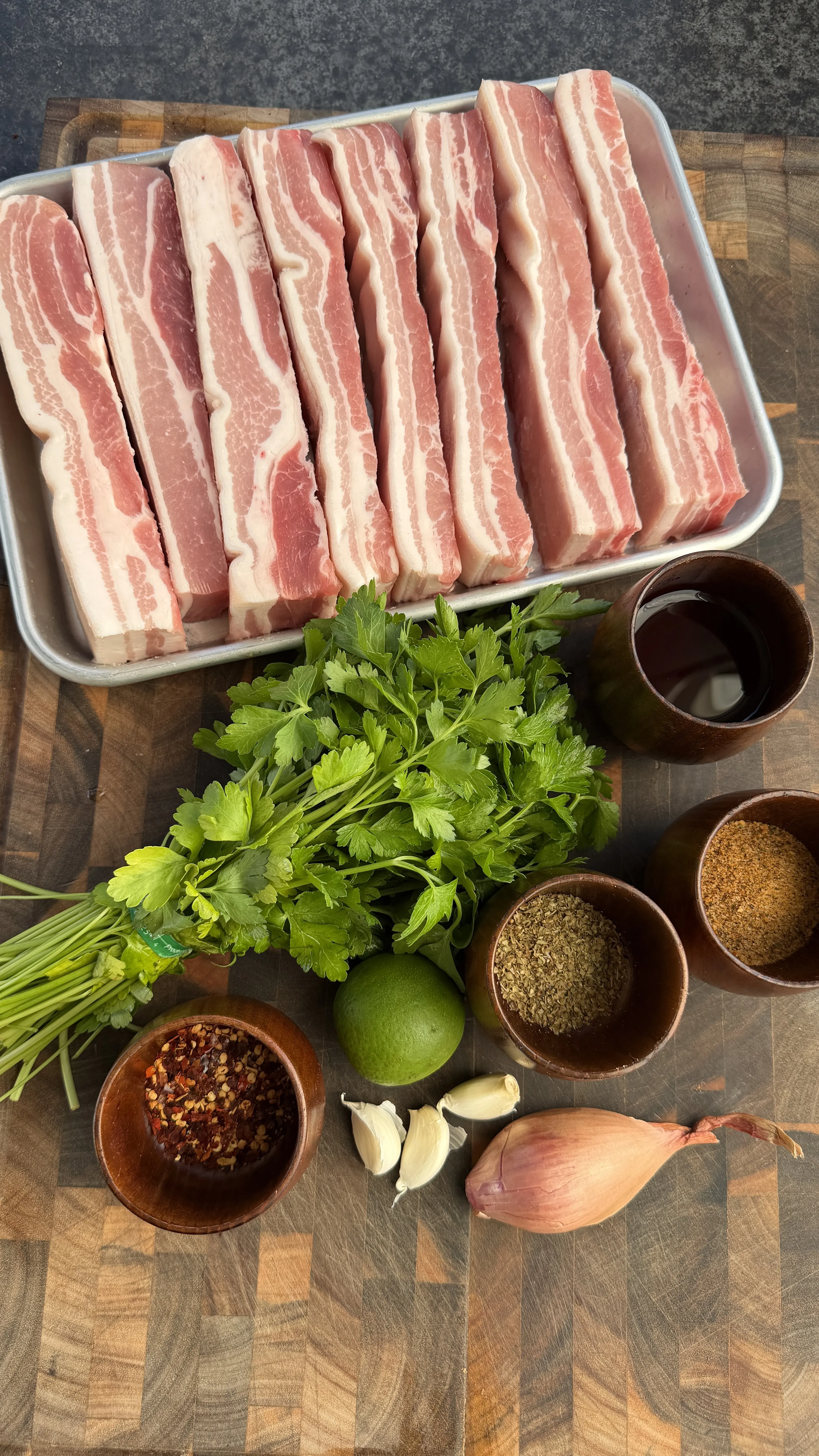 Raw pork belly slices and chimichurri ingredients prep
